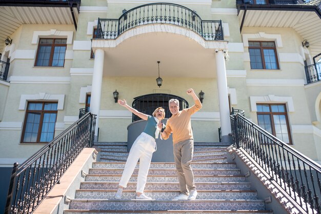 The couple celebrates outside, standing on a staircase in front of a grand building.