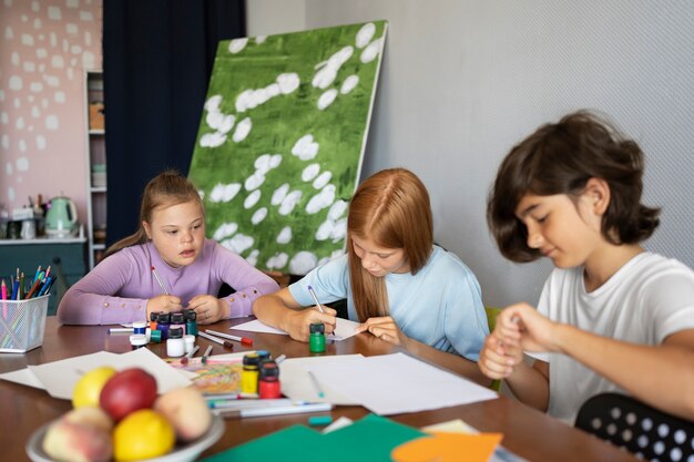Three kids focused on painting and crafting at a table with art supplies in a cozy room.